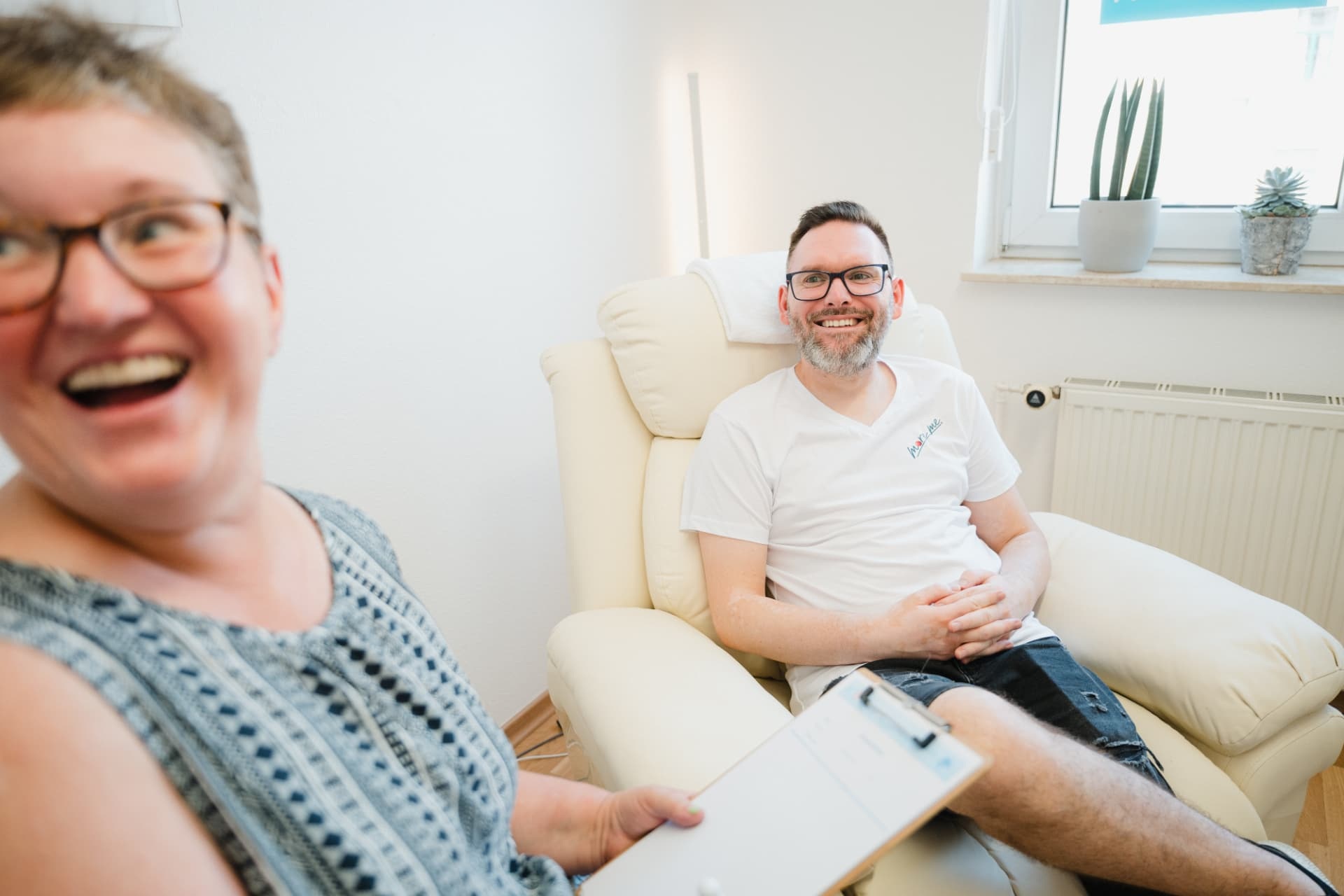 Zwei lachende Teilnehmer bei einer praktischen Hypnoseübung im Seminarraum